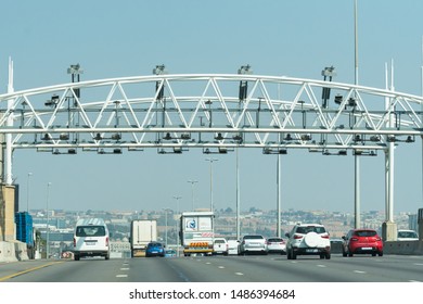 Gauteng, South Africa - August 16, 2019:  Cars And Vehicles Travel Along The Highway Underneath An Open Road Tolling Gantry Which Spans The Road In One Direction And Is Overhead Free Flowing Traffic 