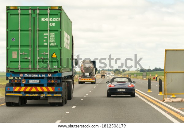 Gauteng,
South Africa - January 20, 2020:  cars and trucks travelling on a
highway that is under road maintenance, concept infrastructure in
Africa with selective focus on the sports
car