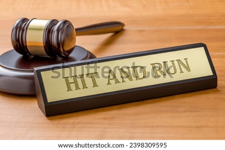 A gavel and a name plate with the engraving Hit and run