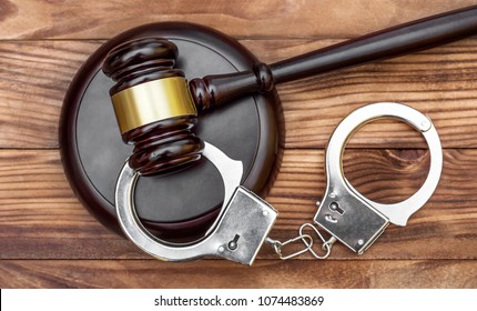 Gavel with stand and handcuffs on the wooden background. Top view.