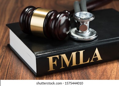 Gavel And Stethoscope Over Law Book Of Family Medical Leave Act On Textured Wooden Surface