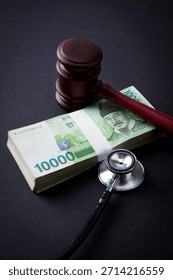 Gavel and stethoscope placed on stack of money in a symbolic representation of law and healthcare in society today