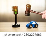 Gavel, toy blue car near a traffic light on the table. Traffic and driving rules concept. Auto accident, drunk driving, court of law, justice