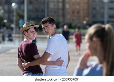 Gay angry teenager couple looking back to surprised woman. Homophobia in adolescence concept.