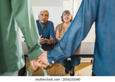 Gay Coming Out Concept With Father And Mother Watching The Homosexual Son With His Boyfriends Hand By Hand Sitting On A Table.