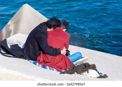 Gay Couple Cuddling By The Sea.