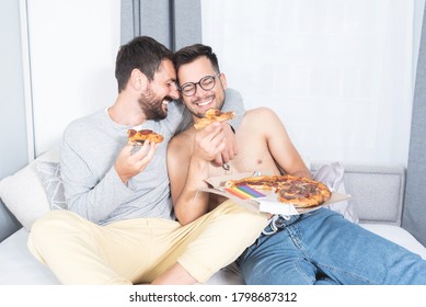 Gay Couple Eating Pizza On Bed At Home