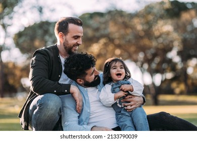 Gay couple enjoying in the park with their little daughter. Proud homosexual family concept. - Powered by Shutterstock