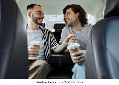 A gay couple enjoys a coffee date in the backseat of a car, holding hands and smiling at each other. - Powered by Shutterstock