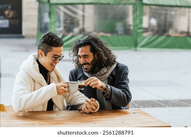 Gay couple holding hands and drinking coffee at outdoor cafe - Powered by Shutterstock