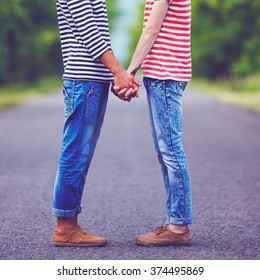 Gay Couple Holding Hands Together On Spring Road