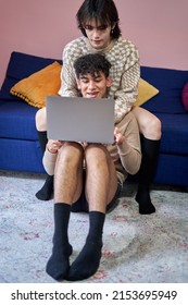 Gay Couple Hugging On Sofa Looking At Laptop