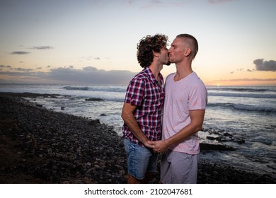 Gay Couple Kissing At The Beach During Sunset In Summer. Same Sex Couple On Vacation, Partners In Love. Romantic And Passionate Moment - Valentine's Day Gay Couple Concept