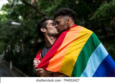 Gay Couple Kissing with Rainbow Flag in the Park