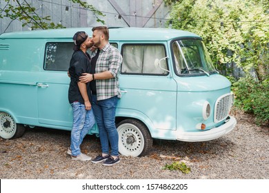 Gay Couple Kissing, Standing Near An Old-fashioned Blue Car Van. Romantic Photo Of Two Men In Love.