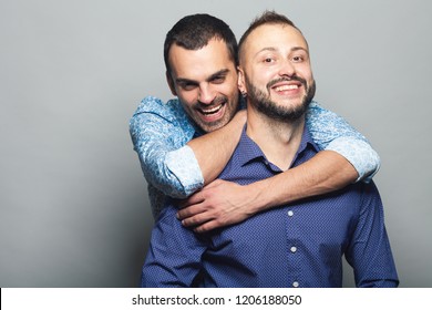 Gay Couple Love, Happy Together Concept. Two Young Men Hugging Each Other And Laughing Over Gray Background. White Shiny Smiles. Close Up. Copy-space. Studio Shot