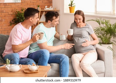 Gay couple with pregnant woman drinking tea at home