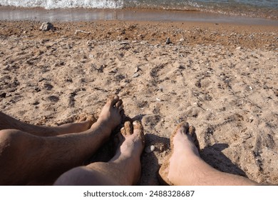 A gay couple is relaxing by the sea, sunbathing on the beach. - Powered by Shutterstock