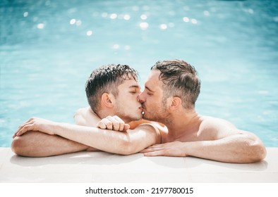 Gay Couple Relaxing In Swimming Pool. LGBT. Two Young Men Enjoying Nature Outdoors, Kissing And Hugging. Young Men Romantic Family In Love. Happiness Concept. 