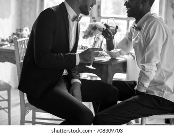Gay Couple Sitting Talking with Wine Glasses Together