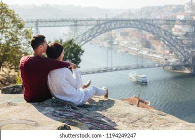 A Gay Couple Traveling And Enjoy Sunset Outdoor, European City View With Bridge And River