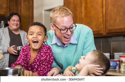 Gay couple with two adorable children laughing in kitchen - Powered by Shutterstock