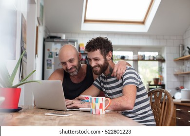 Gay couple using laptop in the kitchen - Powered by Shutterstock