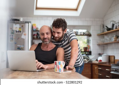 Gay couple using laptop in the kitchen - Powered by Shutterstock