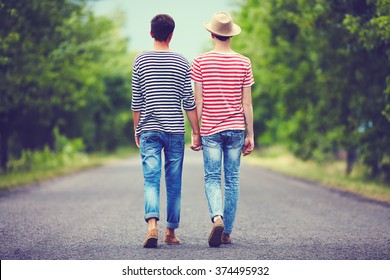 Gay Couple Walking Away Together On Spring Road