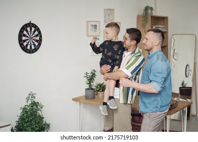 Gay dads playing darts with son