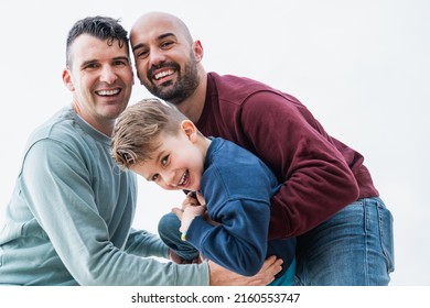 Gay fathers and son having fun together outdoor - LGBT diversity family love concept - Focus on left man face - Powered by Shutterstock