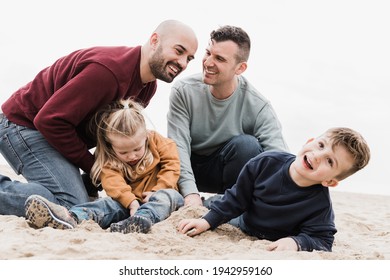 Gay Fathers And Sons Playing On The Beach In Summer Vacation - LGBT Family Love Concept - Main Focus On Left Man Face