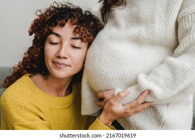 Gay female couple having tender moment listening her pregnant wife baby belly - Lgbt Lesbian family love