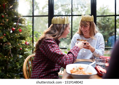 Gay Female Couple Sitting Around Table Making A Toast At Home And Eating Christmas Dinner