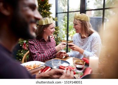 Gay Female Couple Sitting Around Table Making A Toast At Home And Eating Christmas Dinner