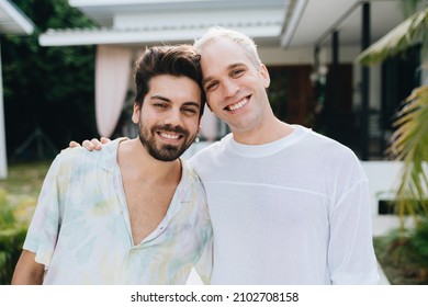 Gay Hugging Couple Standing In Front Of Their House Outdoors