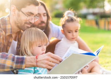 Gay Male Couple With Children Reading A Children's Book.