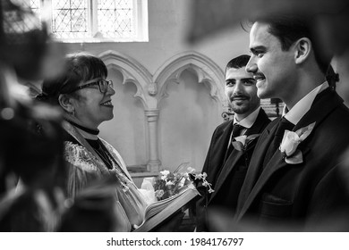 Gay Male Couple Exchanging Wedding Rings In Church With The Vicar Smiling