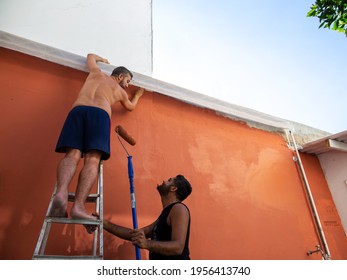 Gay Male Couple Painting The Wall Outside Their Home