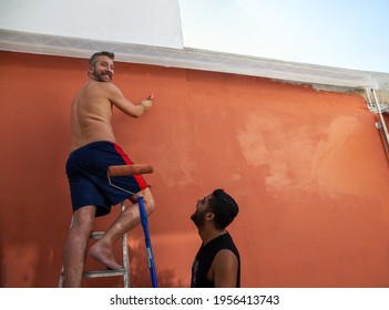 Gay Male Couple Painting The Wall Outside Their Home