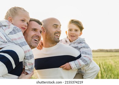 Gay Male Parents Having Fun With Their Sons Outdoor In Summer Day - LGBT Diversity Family Concept - Focus On Left Child Face