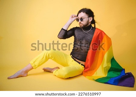 Gay man hold rainbow striped flag isolated on colored background studio portrait. People lifestyle fashion lgbtq concept.