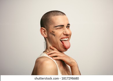 Gay Man Sticking Out Tongue And Winking His Eye. Gender Fluid Man Making Funny Facial Expressions On White Background.