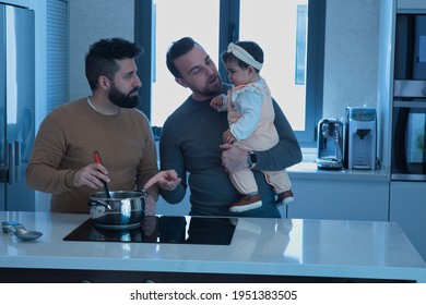 Gay Married Couple Cooking With Their Daughter In The Kitchen Of Their Home. Family Diversity.