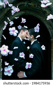 Gay Men Kissing Outside Of Church After Wedding With Confetti Flowers Falling Around Them.