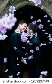 Gay Men Kissing Outside Of Church After Wedding With Confetti Flowers Falling Around Them.