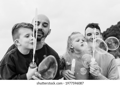 Gay Parents Having Fun With Their Child Sons Outdoor At The Beach In Summer Time - Homosexual Fathers, Sons, Love Family Concept - Black And White Edition