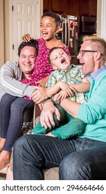 Gay Parents In The Living Room Laugh With Their Children