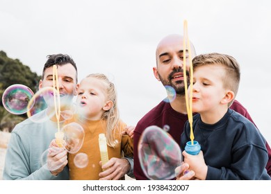 Gay Parents And Sons Having Fun With Soap Bubbles On The Beach During Summer Vacation - Lgbt Family And Love Concept - Main Focus On Right Man Face