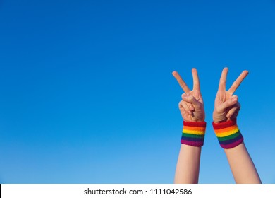 Gay Pride Concept. Hand Making A V Peace Sign With Gay Pride LGBT Rainbow Flag Wristband